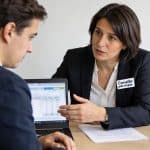 Conseiller pole emploi expliquant calcul allocations a employe assis