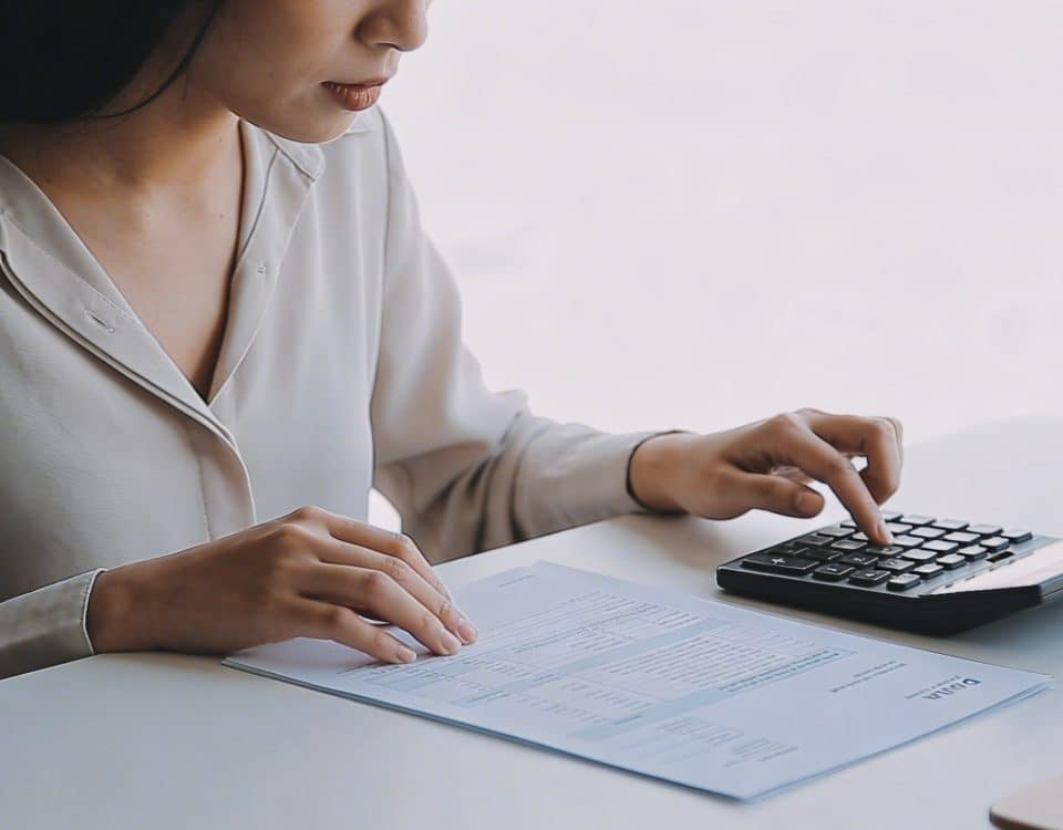 Femme assise a un bureau calculant ses allocations sur un formulaire papier avec une calculatrice