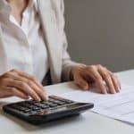 Femme assise a un bureau calculant ses indemnites sur une feuille avec une calculatrice