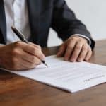 Homme assis signant un contrat officiel sur table
