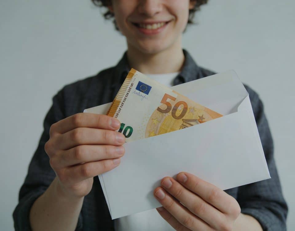 jeune adulte souriant recevant enveloppe de billets euros