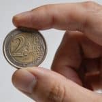 Main en gros plan tenant une piece de deux euros