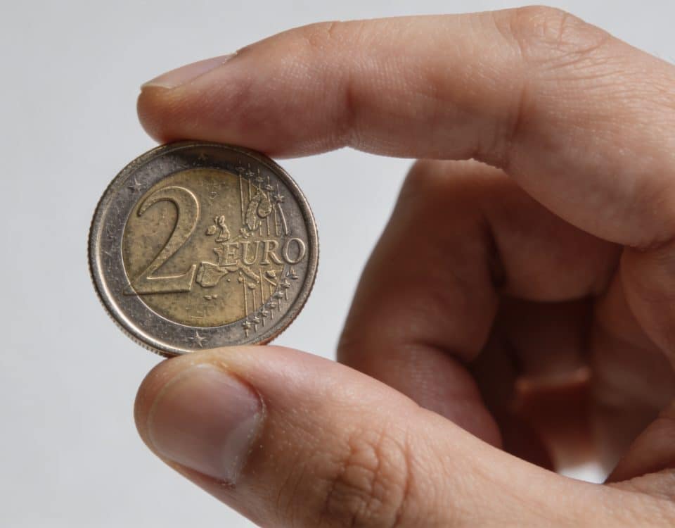 Main en gros plan tenant une piece de deux euros