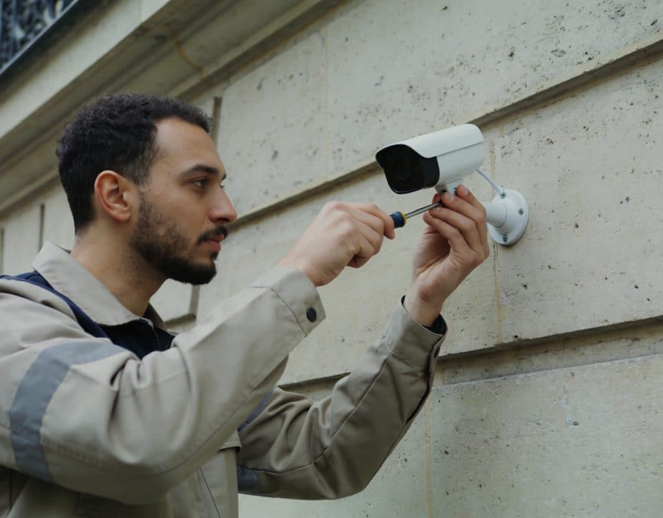 technicien installe petite camera surveillance connectee mur paris
