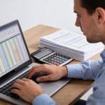 comptable calculant amortissement sur ordinateur avec tableau chiffres