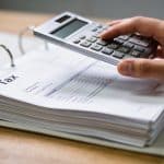 Dossier fiscal ouvert sur bureau, main tenant calculatrice