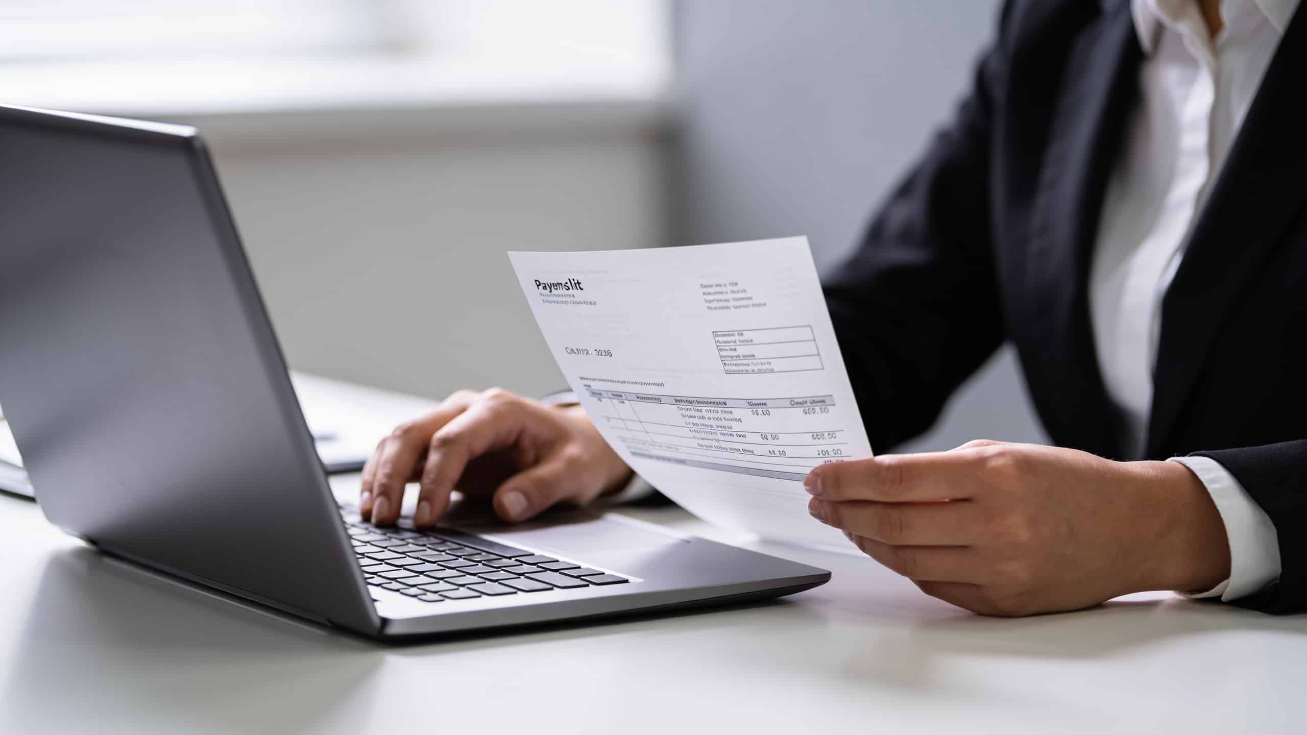 employe assis devant ordinateur consultant fiche de paie