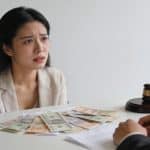 femme anxieuse assise devant un notaire factures étalées