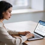 femme assise a un bureau remplissant un formulaire en ligne