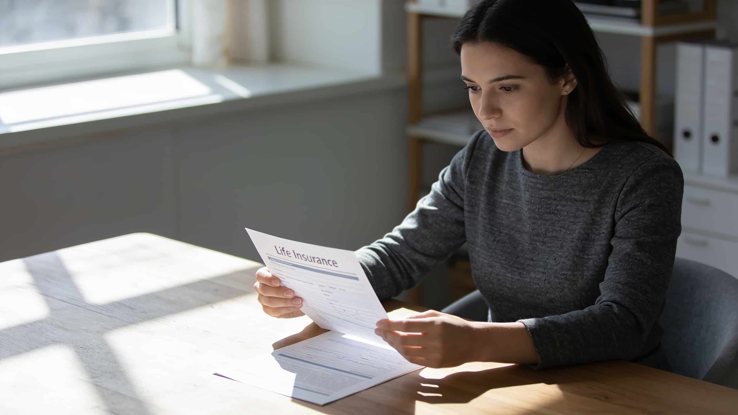 femme examine contrat assurance vie sur bureau ensoleille