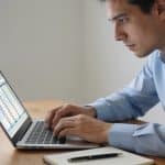 homme en chemise calculant des intérêts sur ordinateur