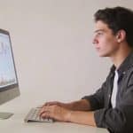 jeune homme assis devant ordinateur analysant graphiques financiers