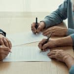 Notaire et couple senior assis signant des documents
