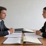deux notaires assis face a face discutant dossiers