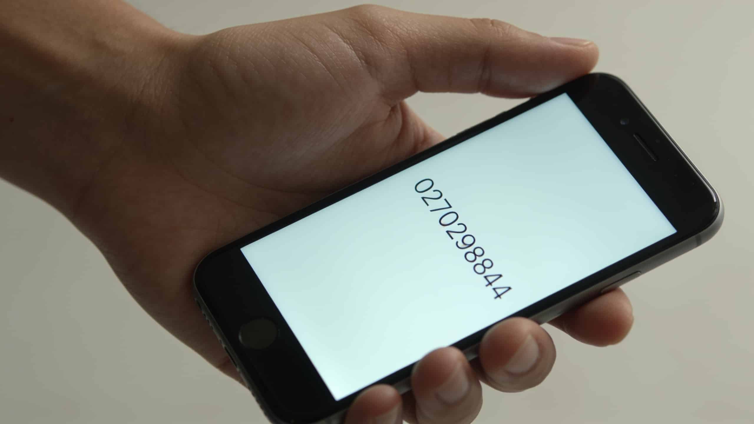 smartphone en main affichant 0270298844 ecran lumineux