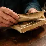 Personne tenant relevé bancaire ancien, argent caché entre pages