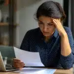 Personne assise à un bureau consultant ses documents salariaux inquiète