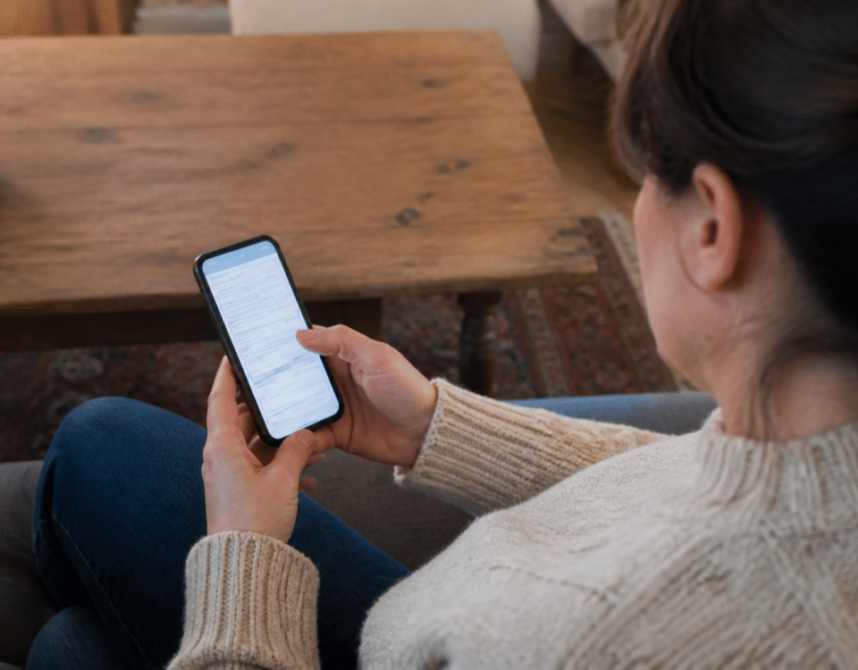 Personne assise tenant smartphone affichant formulaire fiscal impots
