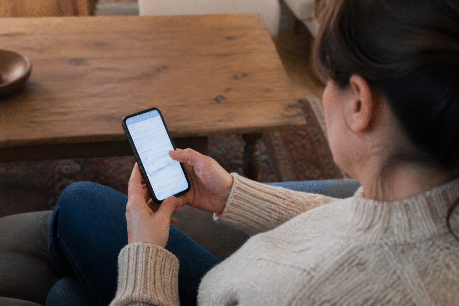 Personne assise tenant smartphone affichant formulaire fiscal impots