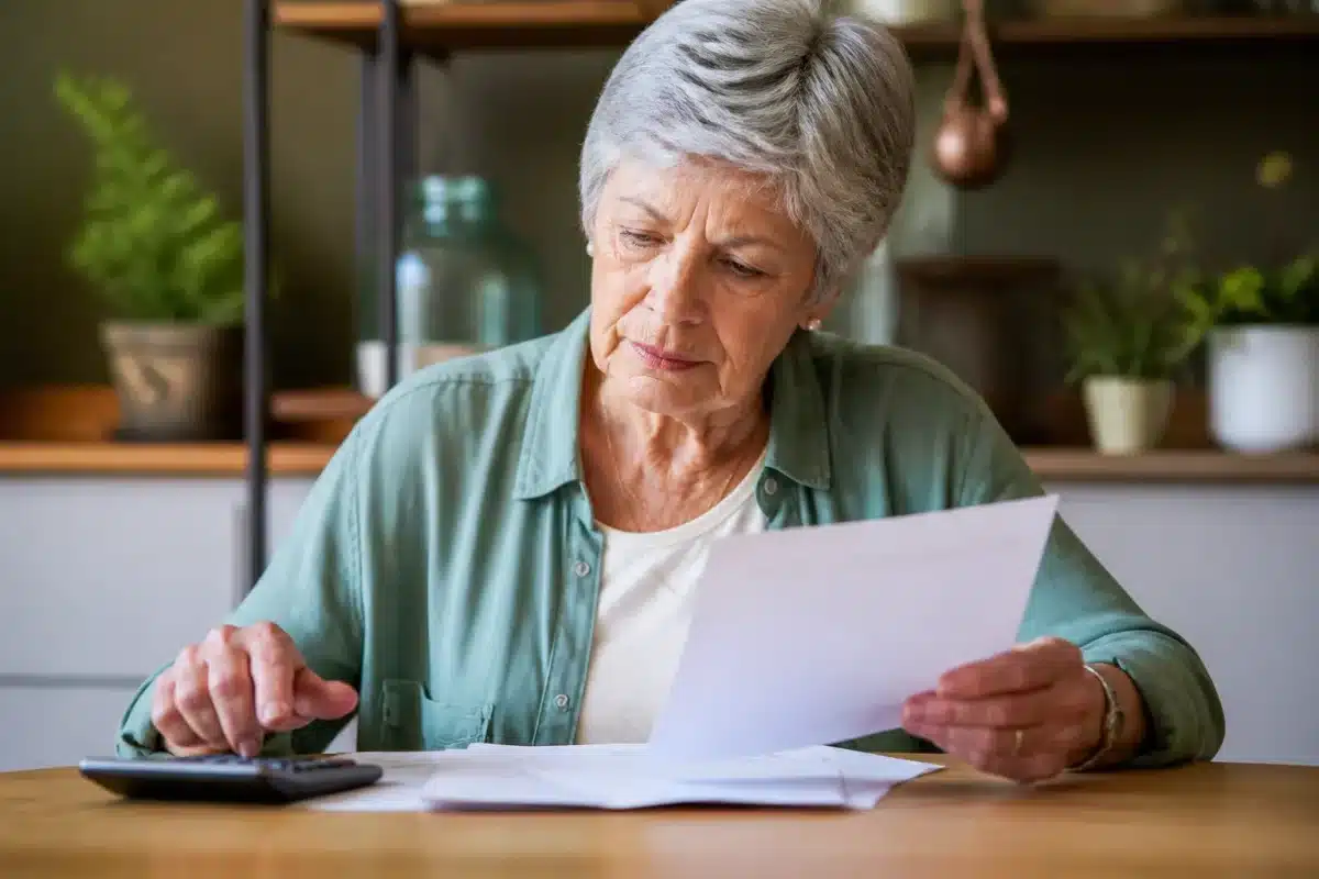 Femme agee consultant documents administratifs avec calculatrice