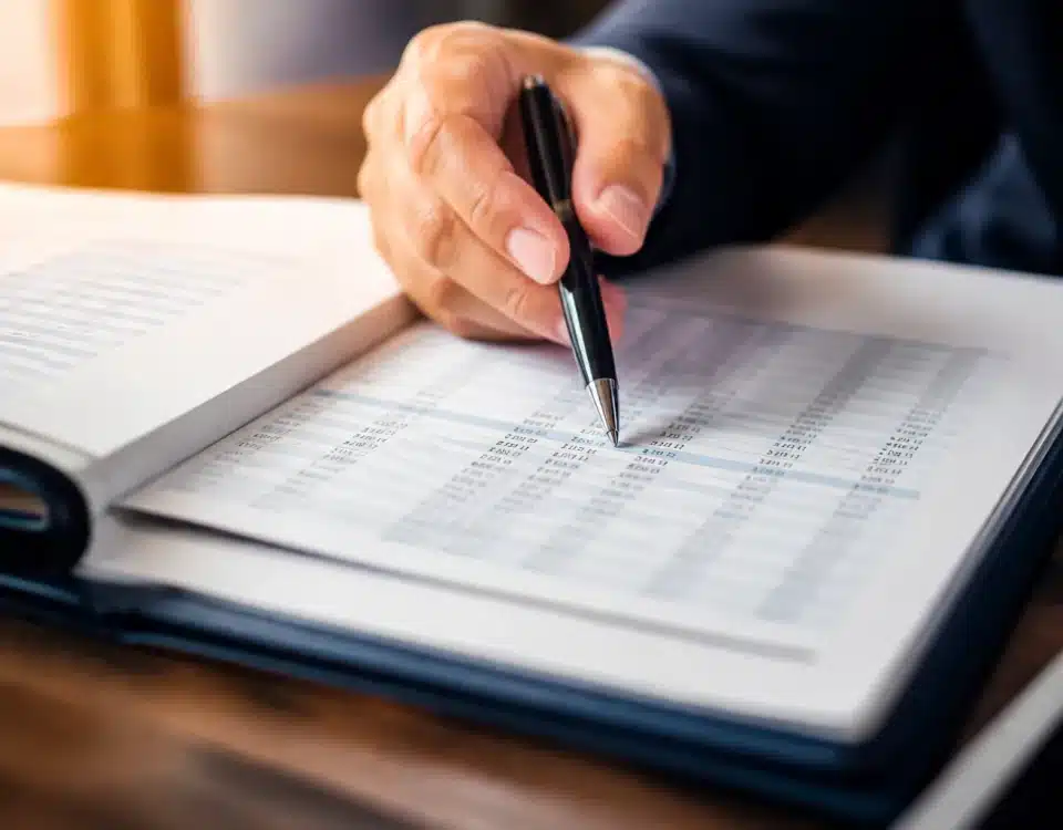 Document notarié ouvert avec stylo pointant sur chiffres financiers détaillés