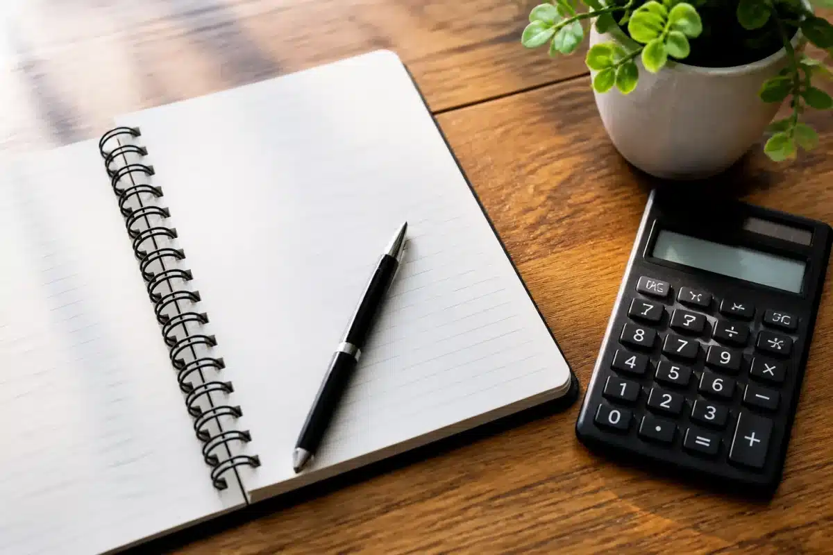 Cahier avec liste de dépenses mensuelles et calculatrice financière