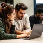 Professionnels assis devant ordinateurs portables collaborant sur projets numériques innovants