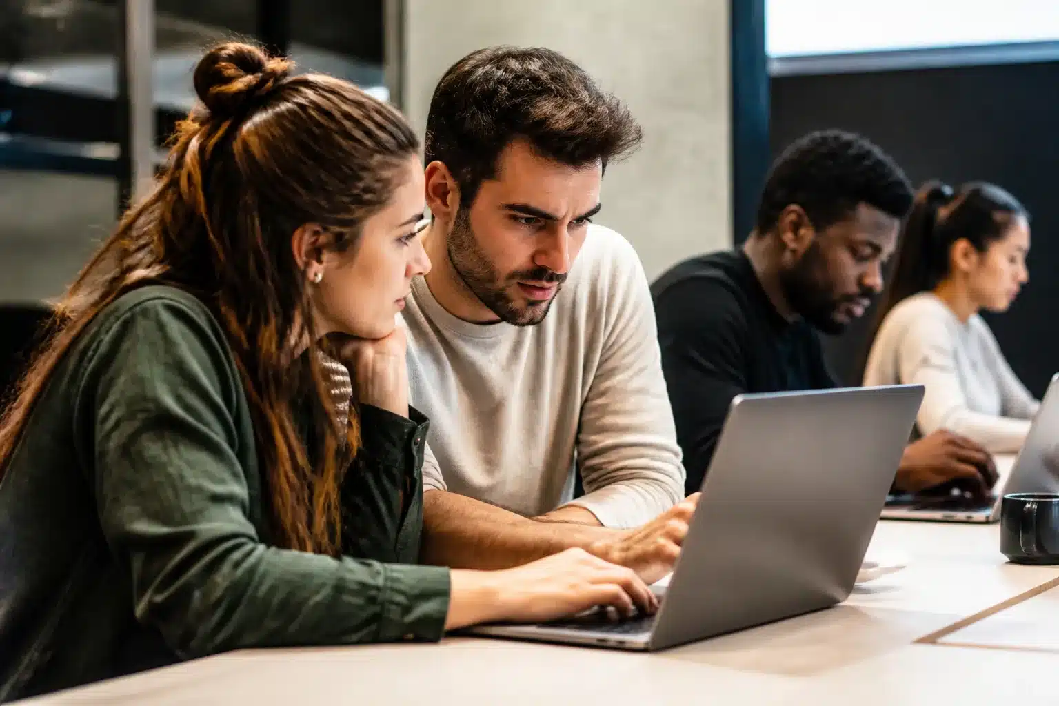 Professionnels assis devant ordinateurs portables collaborant sur projets numériques innovants