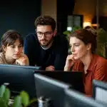 Professionnels assis face ecrans numeriques collaborant ensemble