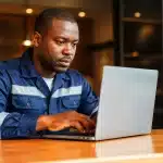 Travailleur en uniforme assis devant ordinateur portable brillant