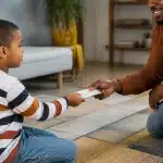 Parent remettant enveloppe argent liquide enfant assis face a face