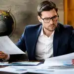Personne assise consultant documents financiers avec globe terrestre visible
