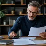 Homme assis a son bureau etudiant documents retraite calculs financiers