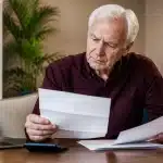 Homme âgé assis consultant documents financiers pension réduction