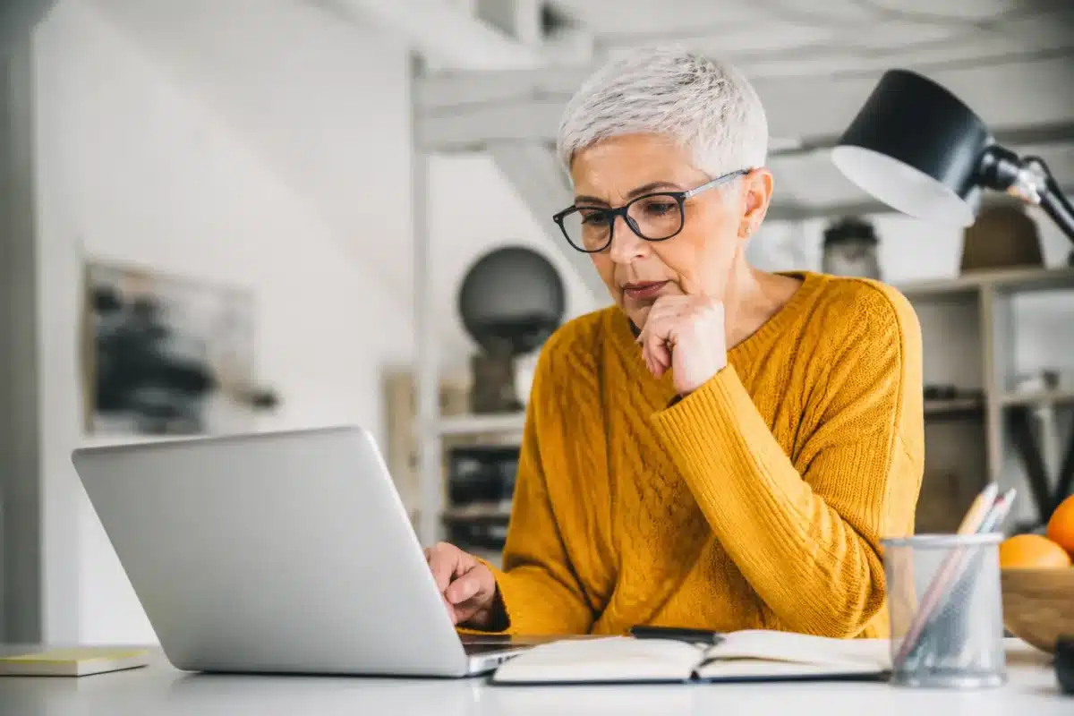 Personne senior consultant documents administratifs sur ordinateur portable