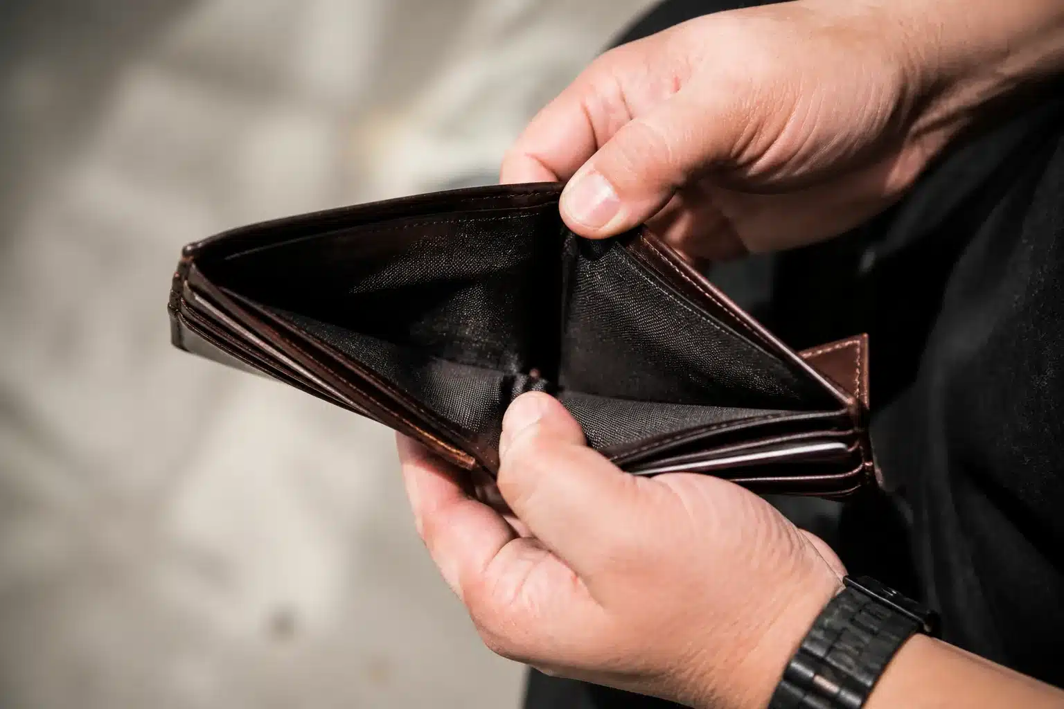 Portefeuille vide ouvert montrant des mains anxieuses sans billets