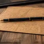 Document manuscrit sur table avec stylo posé dessus horizontalement