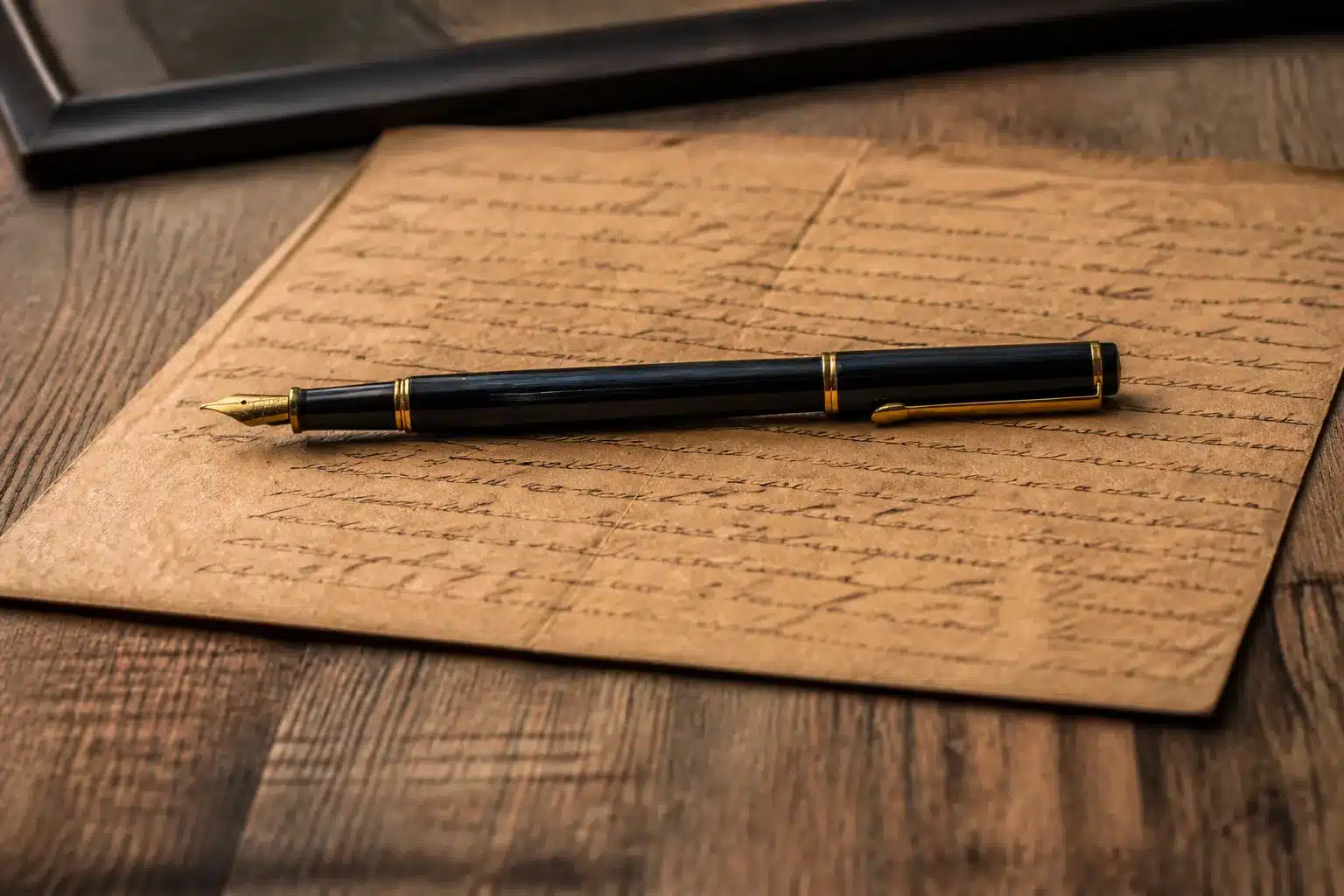 Document manuscrit sur table avec stylo posé dessus horizontalement