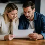 Deux parents examinant ensemble un document administratif sur une table