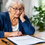 Personne agee assise face a un formulaire d'admission pour maison de retraite