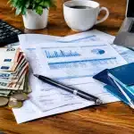 Documents financiers etales montrant salaires, impots et livrets bancaires empiles