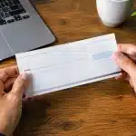 Deux mains tenant un document bancaire au-dessus d'une table