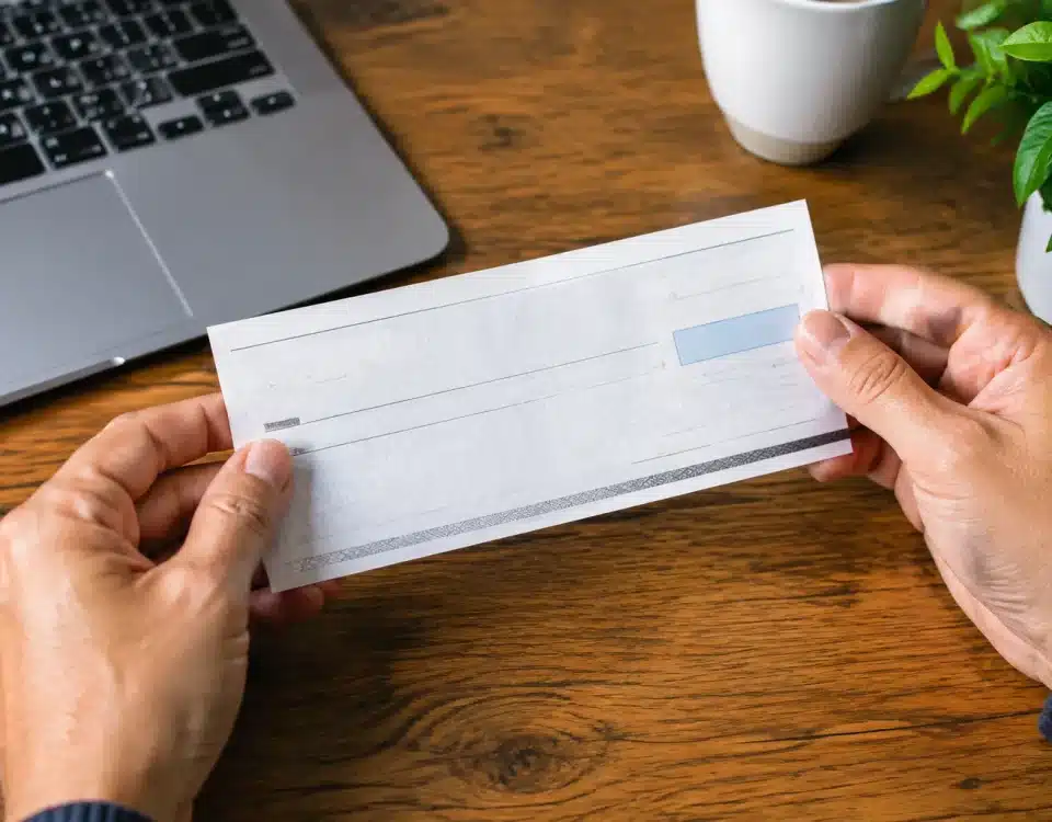 Deux mains tenant un document bancaire au-dessus d'une table