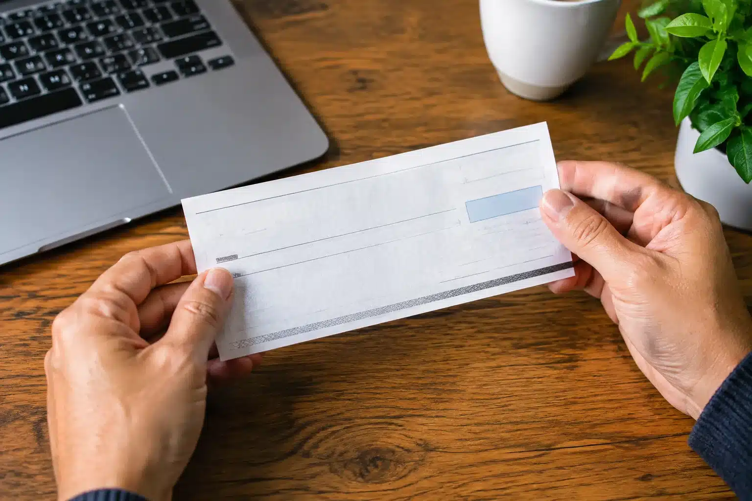 Deux mains tenant un document bancaire au-dessus d'une table