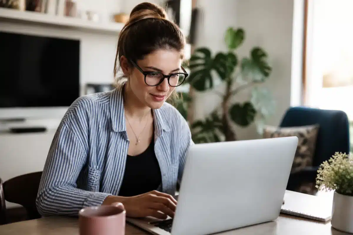 Personne remplissant formulaire sur ordinateur portable chez soi
