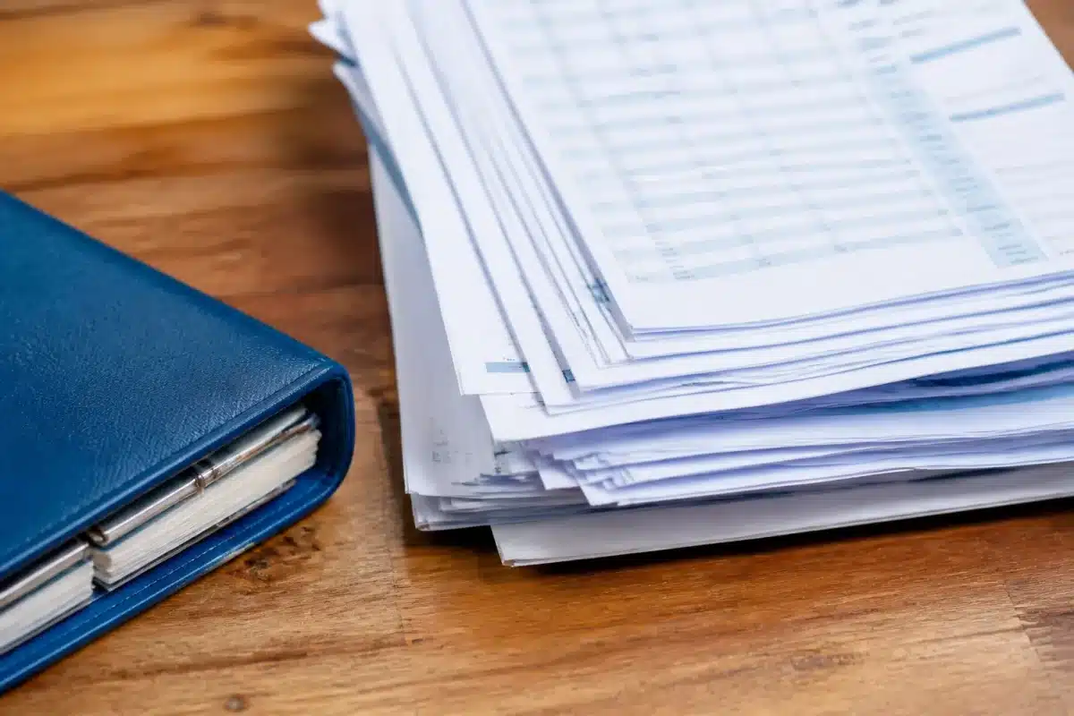 Pile de relevés bancaires et factures avec calendrier bleu
