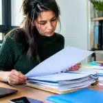 Personne consultant documents administratifs empilés sur bureau