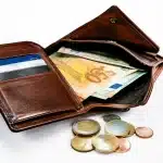 Portefeuille ouvert montrant billets et pieces sur surface blanche