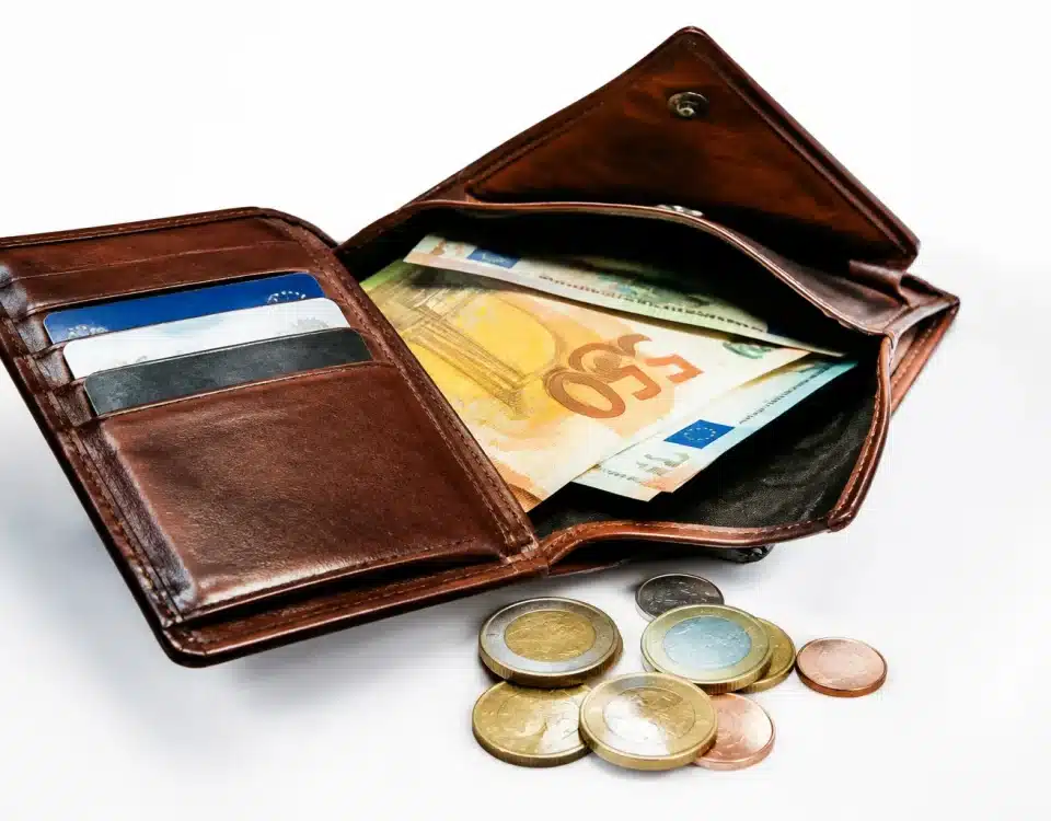 Portefeuille ouvert montrant billets et pieces sur surface blanche