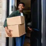 Heritier ouvrant porte maison avec boites cartons dans bras